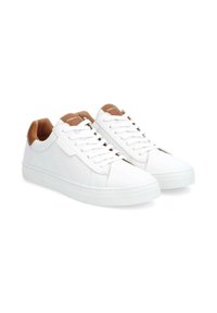 White leather sneakers with tan accents, round toe, flat sole, and lace-up design. Textured rubber outsole for traction.