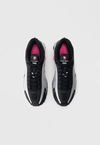 Sneakers Nike Shox w kolorze czarnym i srebrnym, z różowymi akcentami, wiązaniem, wyściełanym kołnierzem oraz teksturowaną gumową podeszwą dla lepszej przyczepności.