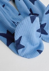 Niebieskie skarpetki o prążkowanej teksturze z ciemnoniebieskimi wzorami w kształcie gwiazd. Długość do kostki z zaokrąglonym noskiem, prezentujące przytulny design.