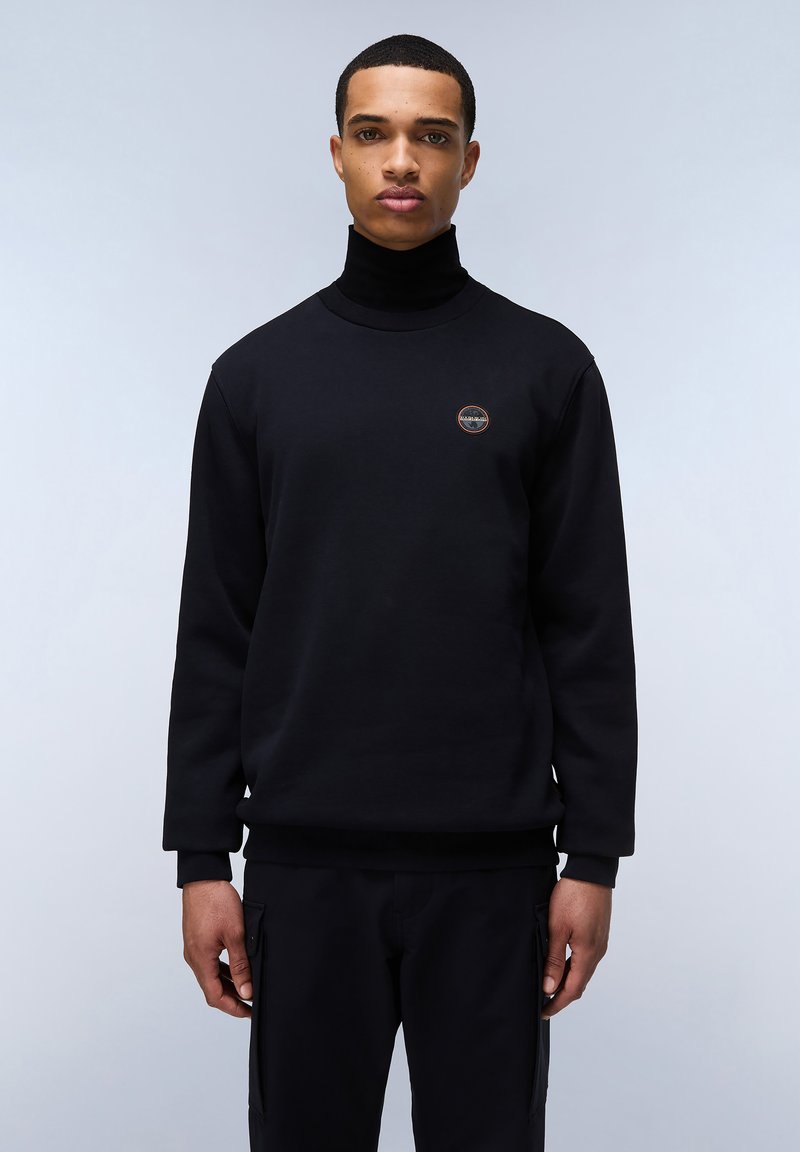 Sudadera negra con cuello alto, puños y cinturilla acanalados. Presenta un logo circular en el pecho. Textura de tela suave, ajuste relajado.