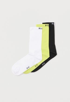 Tres pares de calcetines de canalé a media caña en blanco, verde lima y negro, cada uno con la talla 39-42 impresa cerca de los dedos.