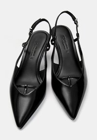 Escarpins noirs à talons avec un design en pointe, en cuir brillant, et des brides fines à la cheville. Présentent un détail découpé à l'avant.