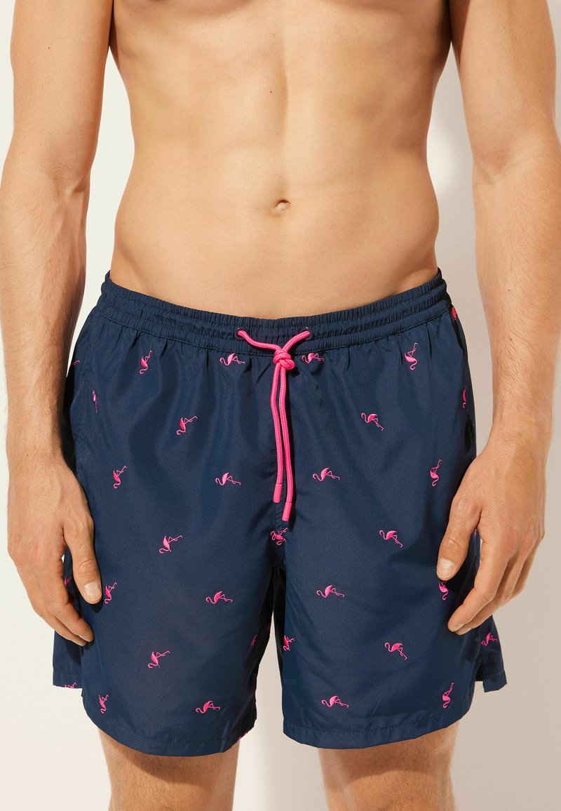 Bañador de color marino con pequeños patrones de flamencos rosas, cintura elástica con cordón y tejido ligero y suave.