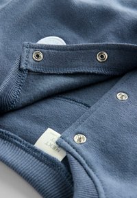 Granatowy sweter z suwakiem w kolorze srebrnym, miękka tekstura i wykończenia szwu. Zawiera biały metkę z nazwą marki.
