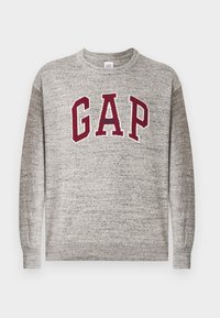 Sivý pulóver s okrúhlym výstrihom a marhuľovými písmenami "GAP" a malým textom "Athletic" umiestneným na hrudi, rebrované manžety a lem.