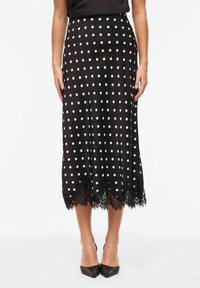 Jupe à pois noirs en satin, avec une bordure en dentelle à l'ourlet, de longueur mi-longue et taille cintrée.