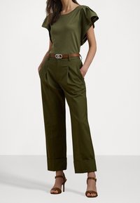 Vihreä oliivinvärinen yläpaita, jossa on leijuvasangat, yhdistettynä korkeavyötäröisiin oliivinvärisiin housuihin, joissa on laskokset ja ruskea vyö metallisoljella.