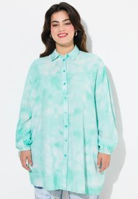 Camicia button-up di un verde acqua chiaro con un motivo tie-dye, maniche lunghe e polsini elasticizzati. Presenta un colletto tradizionale e bottoni lucidi.