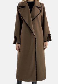 Brauner langer Mantel aus weichem Stoff, mit schwarzem Besatz entlang der Kanten, einem Kragen und weiten Ärmeln. Schöne offene Vorderseite.