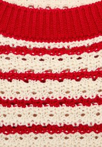 Gebreide trui met afwisselend rode en crèmekleurige strepen, een geribde rode halslijn en een textuur met opengewerkte patronen.