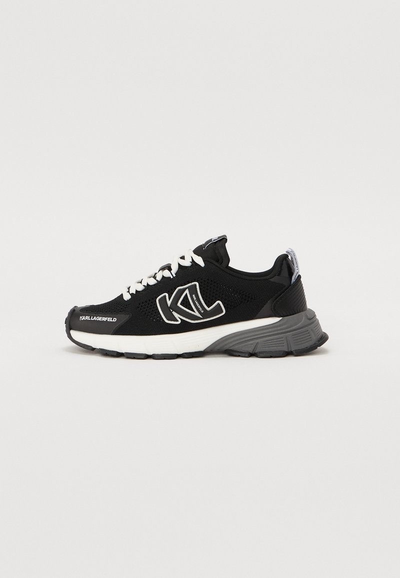 Black athletic sneakers with a breathable mesh upper, white laces, and logo detail. Features a grey cushioned sole and black accents.