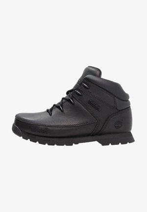 Botte de randonnée en cuir noir avec un col rembourré, un design à lacets, une semelle texturée et le logo Timberland sur le côté. Durable et de hauteur intermédiaire.