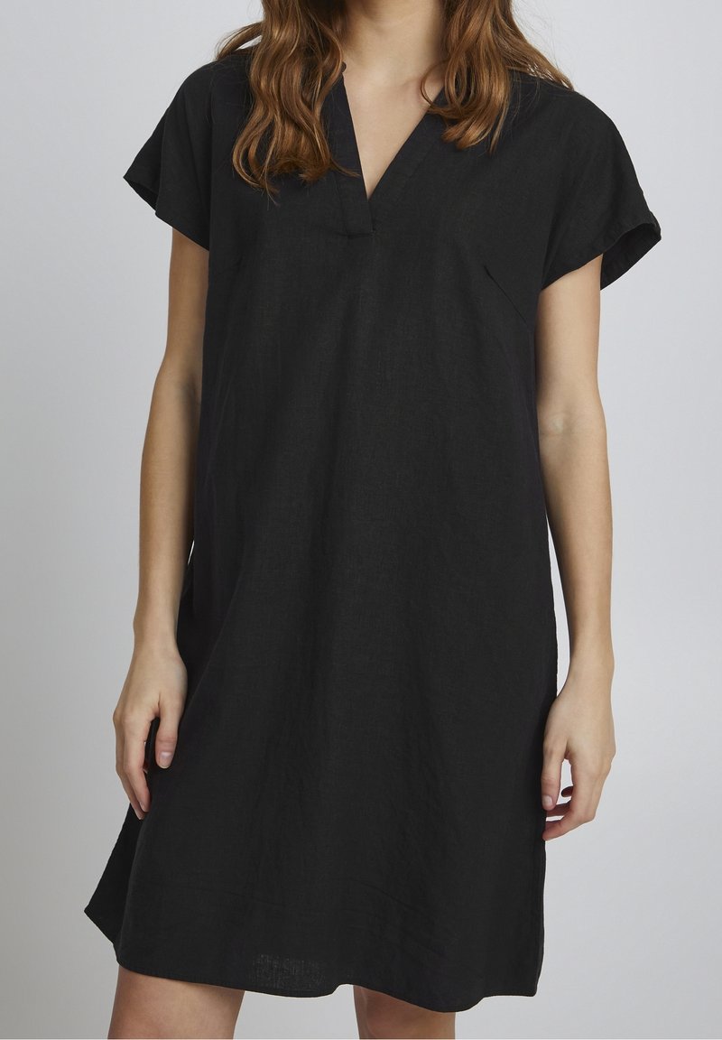 Abito in lino nero con scollatura a V, maniche corte e vestibilità rilassata. Presenta una texture sottile e arriva appena sopra al ginocchio.