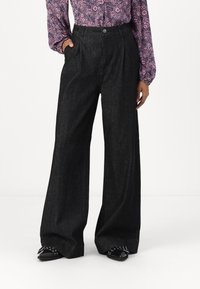 Wide-leg black denim trousers with a high waist, featuring front pleats and a button closure. Smooth texture and casual design.