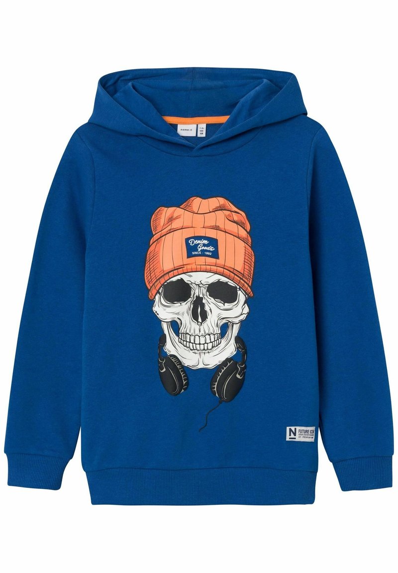 Sweat à capuche bleu avec un motif de crâne portant un bonnet orange et un casque noir sur le devant, poignets côtelés, et une étiquette près de l'ourlet.