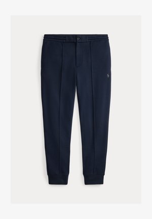 Φόρμες σε ναυτικό μπλε χρώμα από απαλό ύφασμα, με κούμπωμα με κουμπί, δύο πιέτες μπροστά και ριμπ τελειώματα. Κεντημένο λογότυπο στο πόδι.