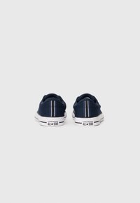 Pair of navy blue Converse All Star sneakers viewed from the back, showing white soles and vertical white stripes on heels.