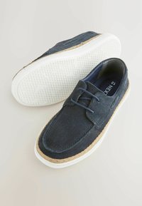 Navy suede kengät kumipohjalla, joissa on kudottu jutee-reunus, nauhakuclosure ja teksturoitu valkoinen ulkopohja, jossa on geometrinen kuvio.