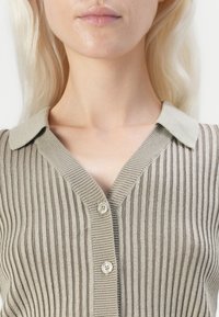 Beige és taupe csíkos kardigán, V-nyakkivágással, rövid gallérral és két gombos záródással, puha, struktúrált kötött anyagból.