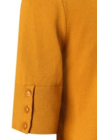 Senfgelbes kurzärmliges Sweatshirt mit strukturiertem Finish und drei braunen Knöpfen am Ärmelabschluss. Hat ein einfaches, klares Design.