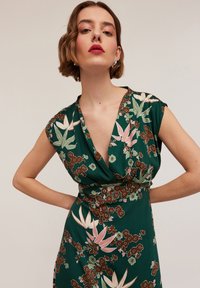 Rochie florală verde cu mâneci scurte, decolteu adânc în V și talie ajustată, având motive florale roz și maro pe o textură satinată.