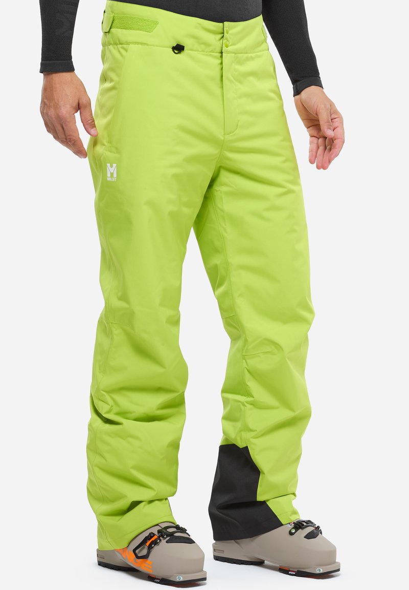 Limonengrüne Skihosen aus wasserdichtem Material, mit lockerer Passform, Reißverschlusstaschen und einem Logo am Bein; getragen mit Skischuhen.