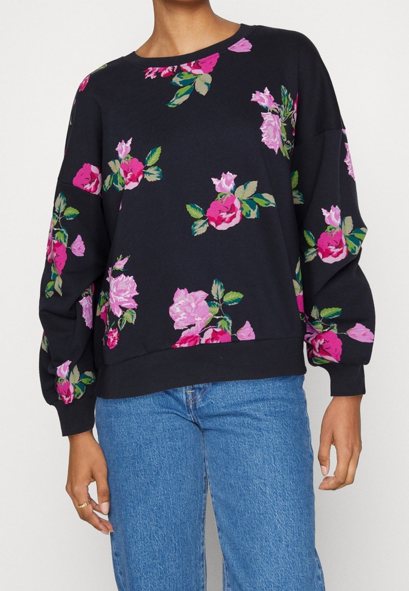 Dark blue sweatshirt with a crew neck, featuring large, colorful floral patterns in pink and green. Soft fabric and long, loose sleeves.