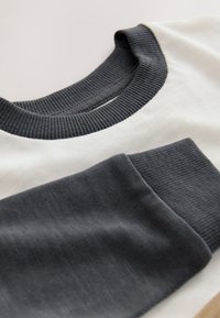 Crewneck sweatshirt featuring a gray ribbed collar and cuffs, with a white body section. Material appears soft with a smooth texture.