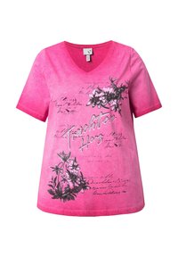 Camisa de cuello en V rosa con gráficos florales y diseños de texto manuscrito, acentuada con pequeñas piedras brillantes en una tela suave y texturizada.