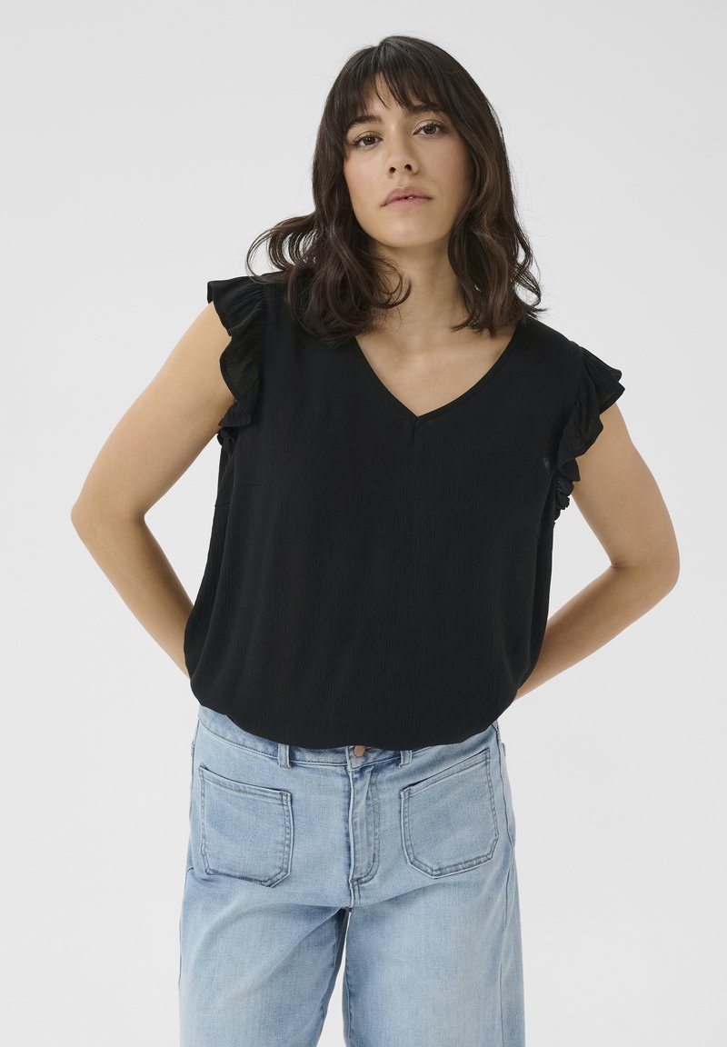 Blouse noire à col en V avec des manches volantes, texture douce, coupe décontractée, assortie à un jean en denim bleu clair. Fond uni.