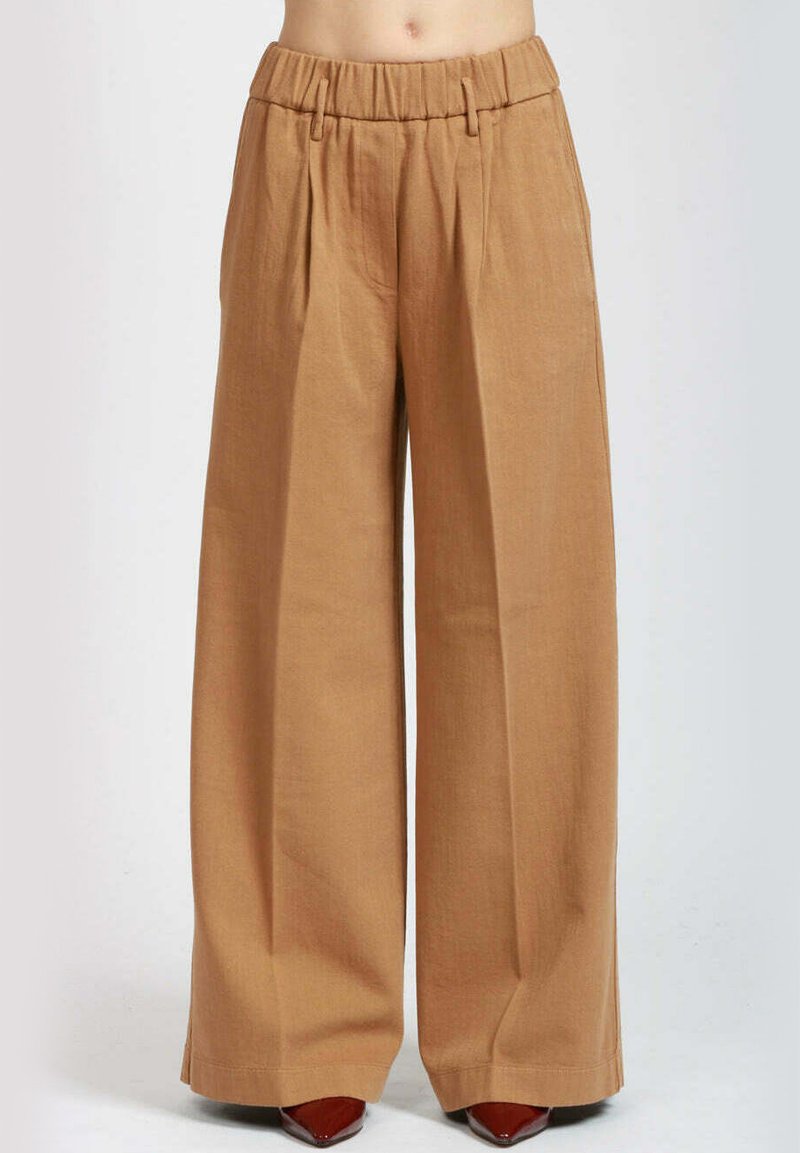 Pantaloni a gamba larga in un tessuto marrone chiaro, caratterizzati da un frontale plissettato, una vita elastica e una consistenza liscia. Design semplice e sartoriale.
