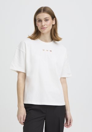 Fehér pamut rövid ujjú póló, kerek nyakkivágással és három kis szív alakú kivágással vízszintes sorban a mellkason.