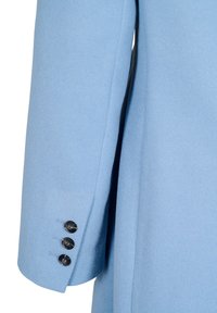 Svetlo modri volneni plašč z oblikovanim krojem. Ima enojno rebro in črne gumbe na manšeti. Mehka tekstura, ravno krojene rokave.