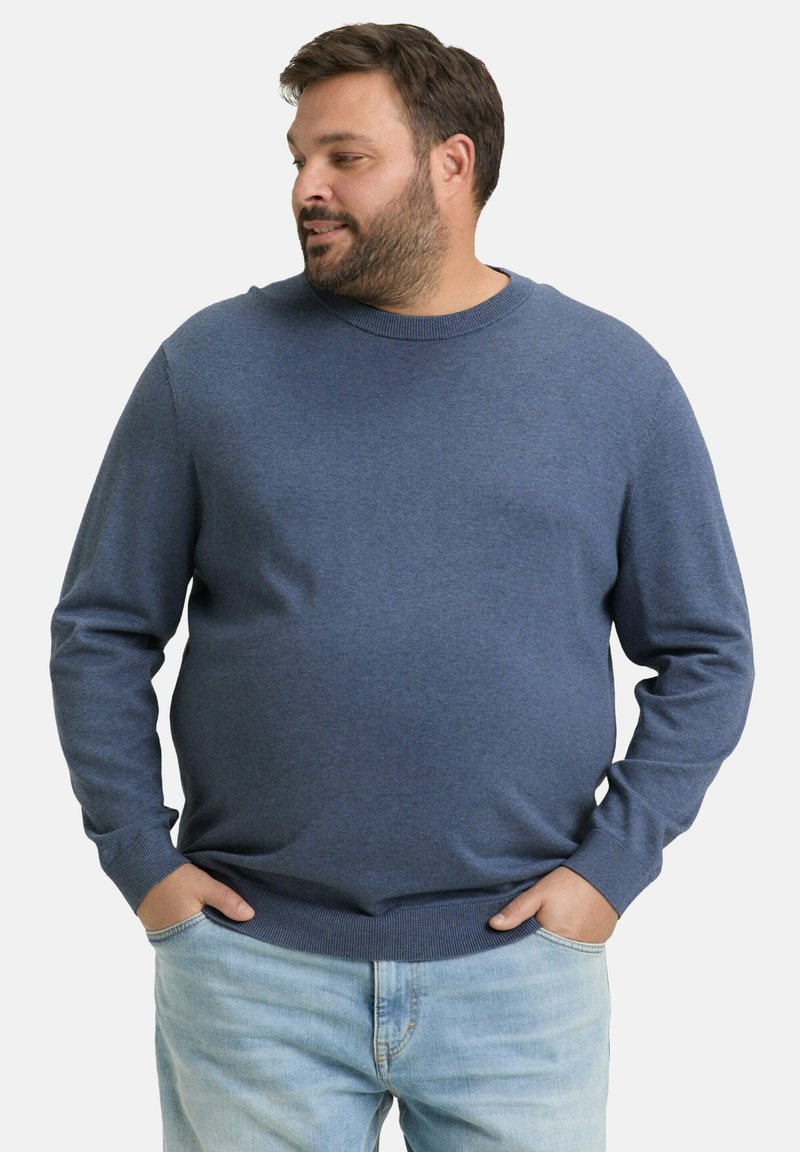 Dunkelblauer Strickpullover mit rundem Halsausschnitt und gerippten Bündchen. Kombiniert mit hellblauen Jeans, hat er eine lockere Passform und eine glatte Textur.