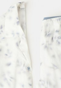 Ensemble de pyjama blanc avec un motif floral bleu clair, comprenant une chemise boutonnée à col et un pantalon à taille élastique.