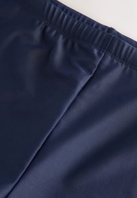 Close-up van marineblauwe stof met elastische tailleband en zichtbare naadstiksels.