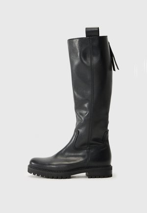 Botte en cuir noir, hauteur genou, avec une finition lisse, un embout renforcé et une semelle en caoutchouc. Elle comprend des détails de couture et une languette en haut.