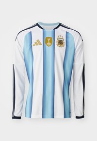 Camisola de futebol de mangas compridas em branco com riscas verticais azul claro e azul escuro. Apresenta os logótipos dourados da FIFA e da AFA, e detalhes em preto.