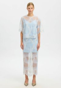 Ensemble en dentelle composé d'un haut bleu clair à manches courtes et d'une jupe assortie, tous deux ornés de motifs complexes et d'une texture transparente.