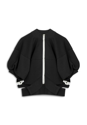 Zwarte oversized sweatshirt met een hoge kraag en een rits aan de voorkant. Heeft ruime mouwen en witte hardware-accenten aan de onderkant. Zachte textuur.