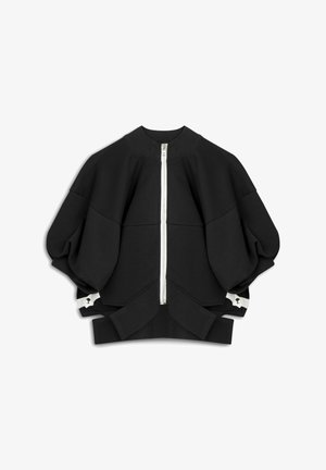 Schwarzer übergroßer Sweatshirt mit hohem Kragen und durchgehendem Reißverschluss. Mit weiten Ärmeln und weißen Hardware-Details am unteren Rand. Weiche Textur.
