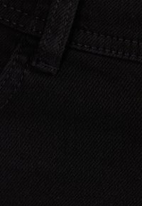 Svart denimtyg med en slät yta, försedd med mörka sömmar och en synlig bältesöggla. Ytan visar ett subtilt diagonalt vävningsmönster.