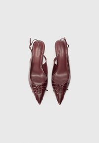 Burgundy nahka slingback-korkokengät teräväkärkisellä muotoilulla, joissa on sidottu nauhatyyny ja ohuet hihnat. Sileä pinta ja minimalismi suunnittelu.