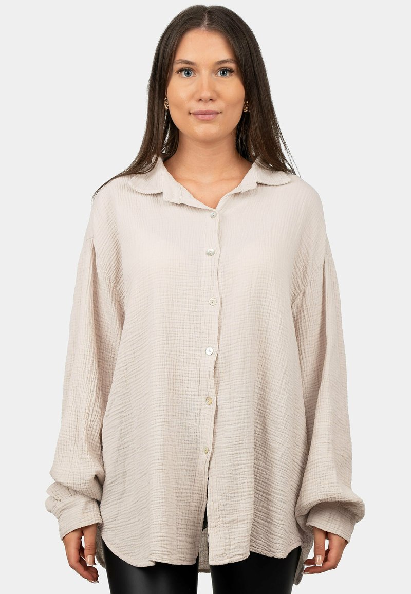 Lichtbeige overhemd met knoopsluiting, gemaakt van geweven, gekreukeld materiaal. Voorzien van een kraag, lange mouwen en een comfortabele pasvorm. Zacht, casual stijl.