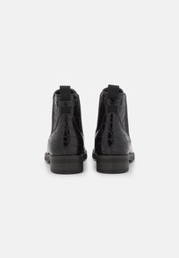 Musta Chelsea-nilkkurit lakattua nahkaa, jossa on krokotiilinkuosiset yksityiskohdat, elastiset sivupaneelit ja matala lohkokorko.