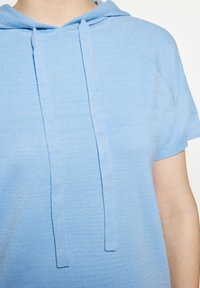 Világoskék, rövid ujjú kapucnis felső, texturált anyagból, elülső kenguruzsebbel és két húzózsinórral a nyakán a beállításhoz.