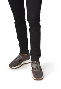 Sneakers in camoscio grigio scuro e mesh con lacci grigio chiaro e suola avorio, indossate con pantaloni neri attillati.