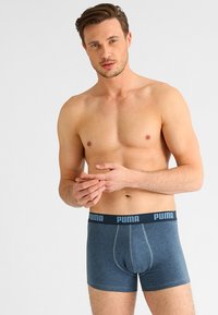 Boxer shorts de algodón azules con un logo de Puma en la cintura negra, que presentan un diseño ajustado y detalles de costura visibles.
