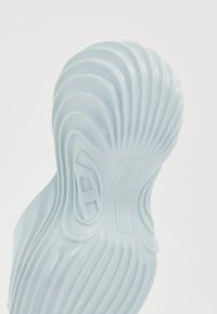 Light blue footwear with a wavy, textured surface. Features embossed branding on the bottom and a contoured design for comfort.