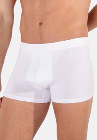 Białe bawełniane bokserki z miękkim paskiem wytłoczonym logo, gładką fakturą, dopasowanym krojem i długością do połowy uda.